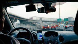 Motorista de aplicativo feliz dirigindo um carro protegido com seguro Suhai, contratado online pela ComVida Seguros.