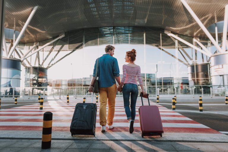Casal com malas no aeroporto prontos para embarcar para Europa com seguro viagem