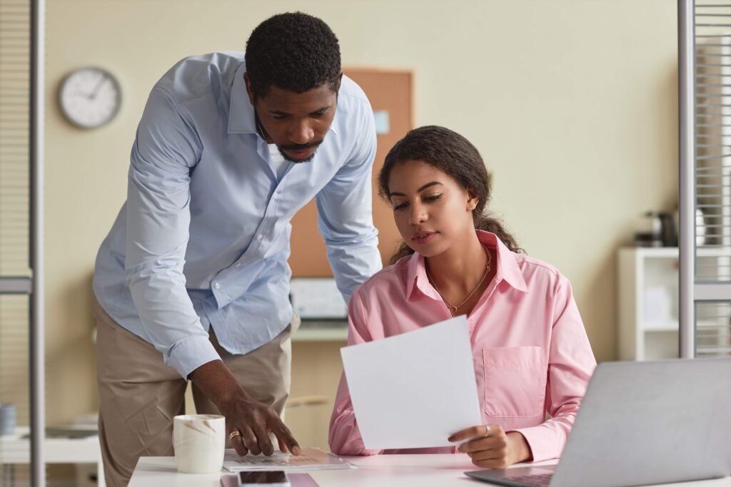Jovem estagiário sendo orientado por um profissional em ambiente de trabalho