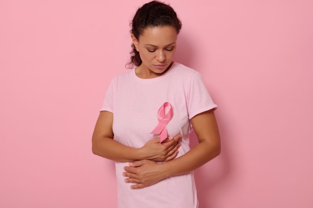 Mulher usando rosa com laço símbolo do Outubro Rosa em sinal de prevenção ao câncer de mama.