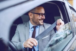Motorista sorridente no carro após renovar o seguro do carro mais barato
